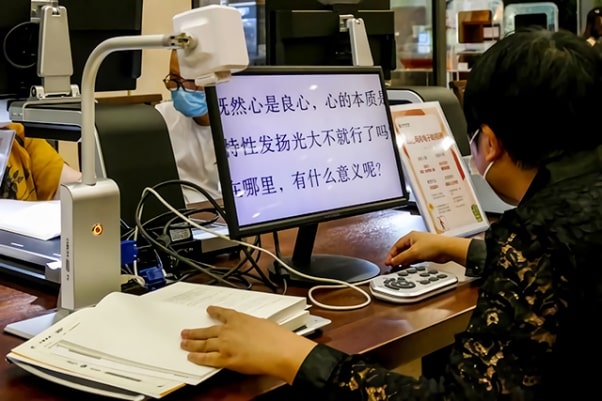 低视力读者在杭图无障碍阅览室借助远近两用便携式电子助视器阅读